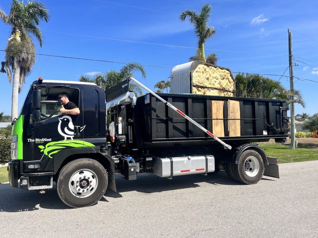 Actual Lee Dumpster Rentals truck and black container Actual black walk-in dumpster truck and container in a Southwest Florida driveway